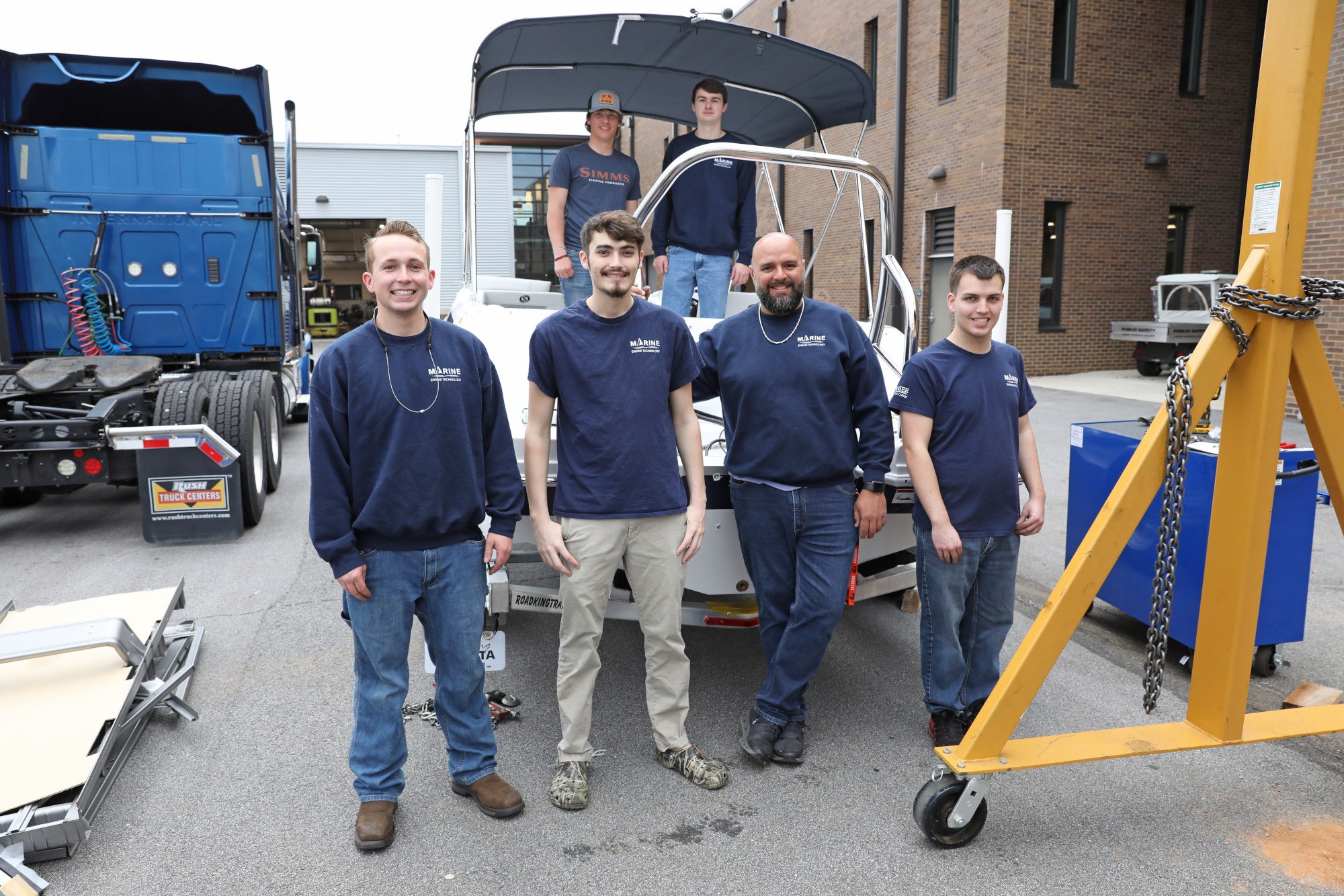 Marine Engine Technology Students standing on and around a boat