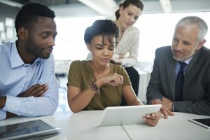 Four professional people looking at a computer tablet