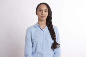 A young woman with long dark hair is staring optimistically at the camera
