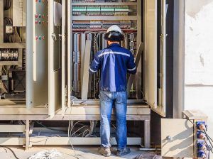 Instrument technician on the job check wiring on PLC cabinet