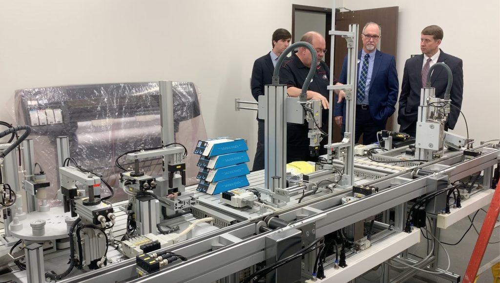 Joey Watkins explains the importance of advanced PLC manufacturing line training to Commissoner Dozier as TCSG Asst. Commissioner Neil Bitting and Dr. Perren look on.