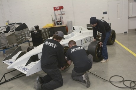 Photo of Motorsports Vehicle Technology students changing tire on Formula One race car in the new Hall Campus MVT shop.