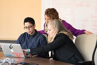 Three people looking at laptop screen