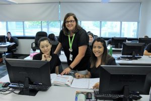 Instructor assisting two female students in computer lab