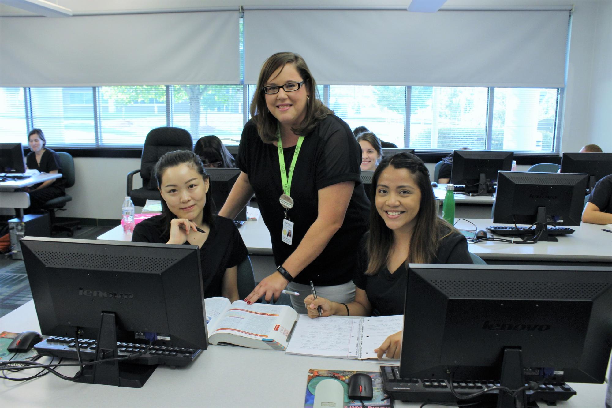 Instructor assisting two female students in computer lab