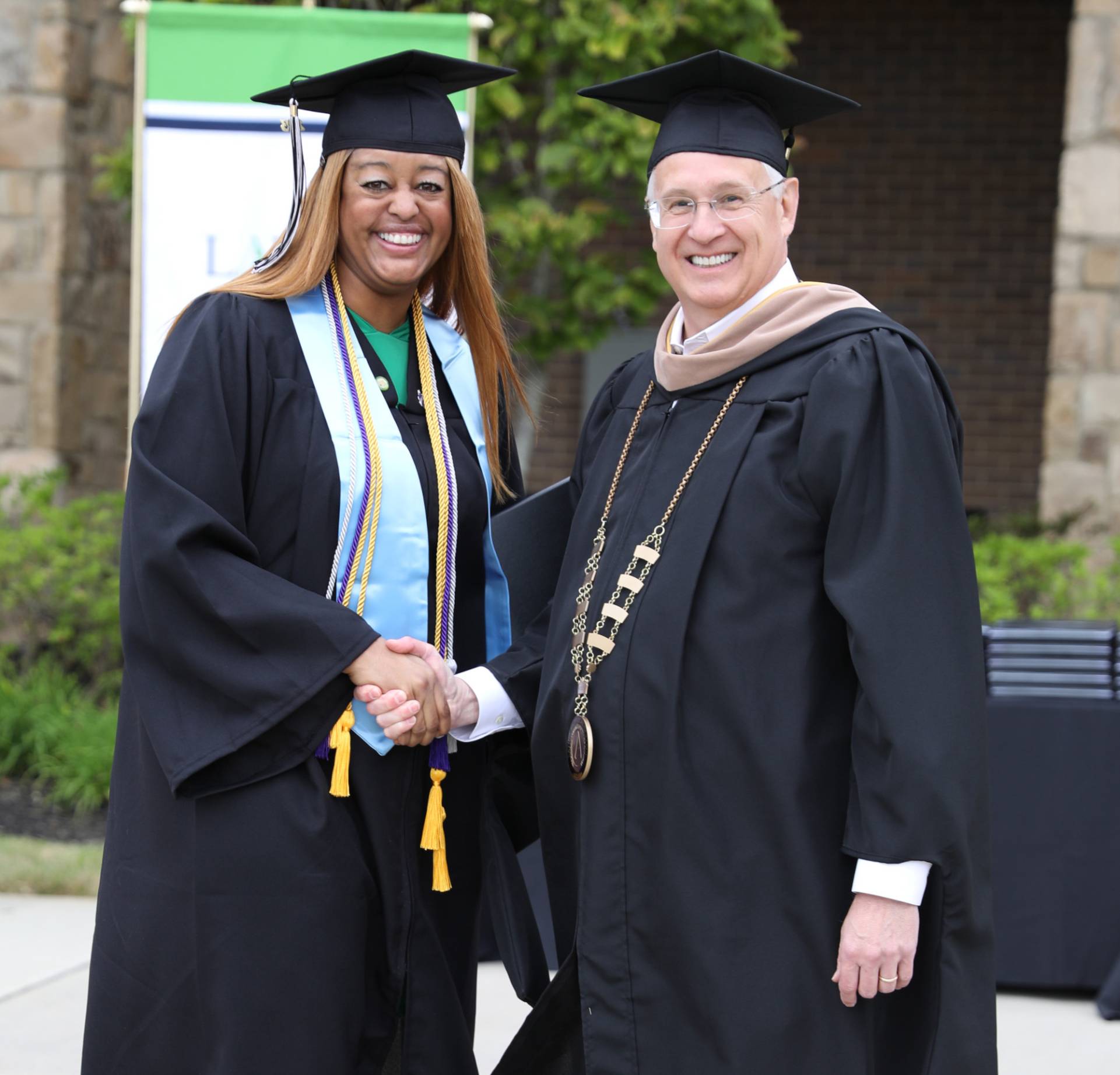 President Tim McDonald shaking hands with graduate